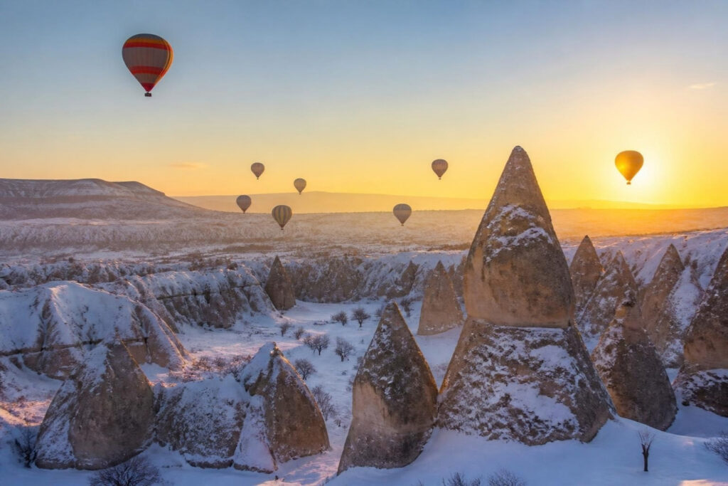 Balões de ar quente ao nascer do sol sobre a Capadócia com neve